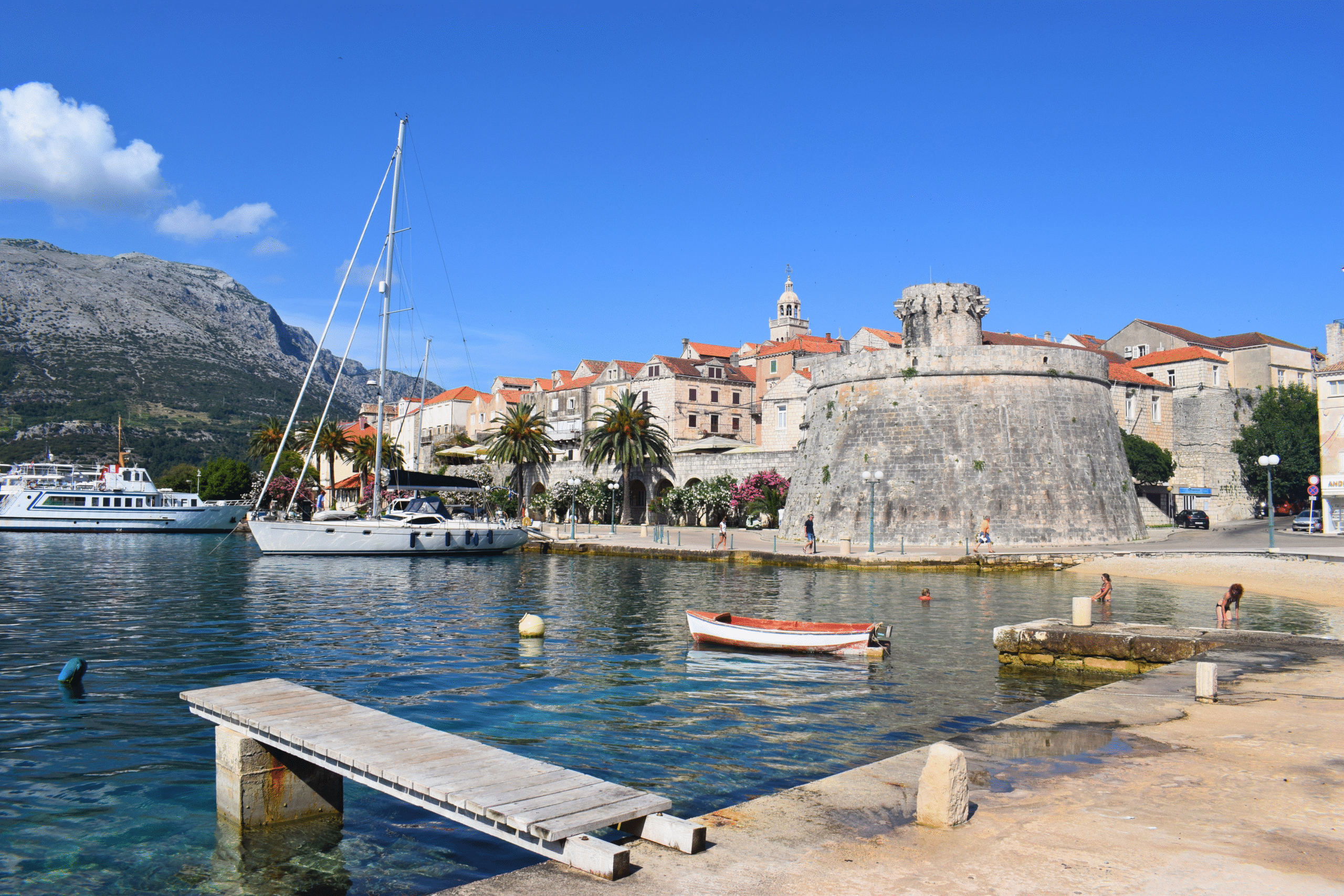 harbor with historic buildings and people swimming in Korčula