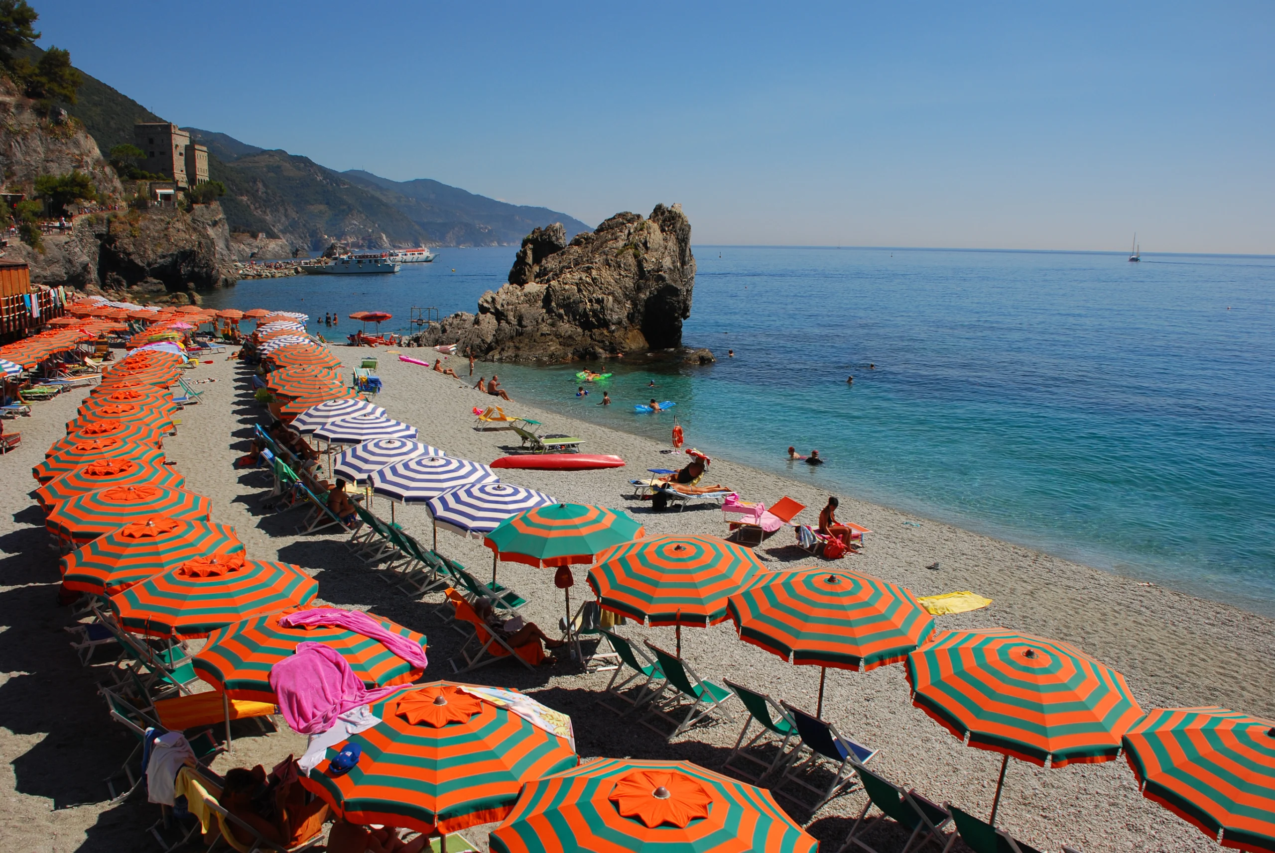 Summer Holiday on Italian Riviera with bright orange green umbrella at Liguria region, Italy.