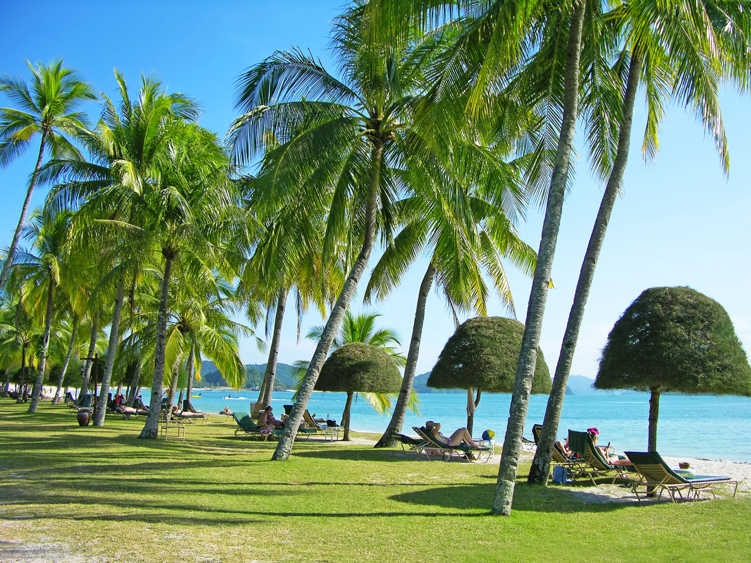 Cenang beach, Langkawi, Malaysia. Relaxing tropical beach with palm-trees and sunbeds, Langkawi island, Malaysia