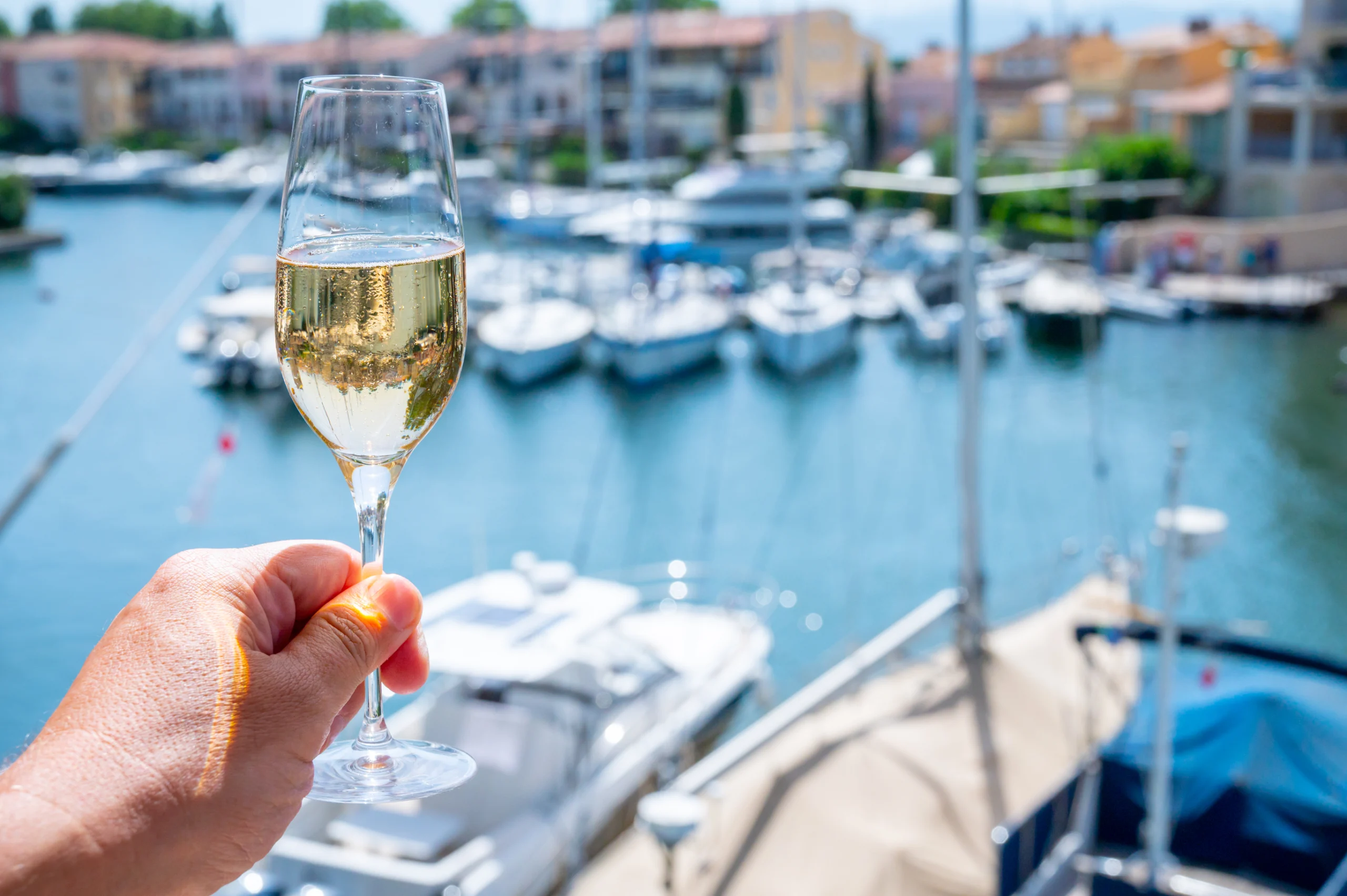 drinking of French brut champagne sparkling wine in glasses in yacht harbour of Port Grimaud near Saint-Tropez, French Riviera.