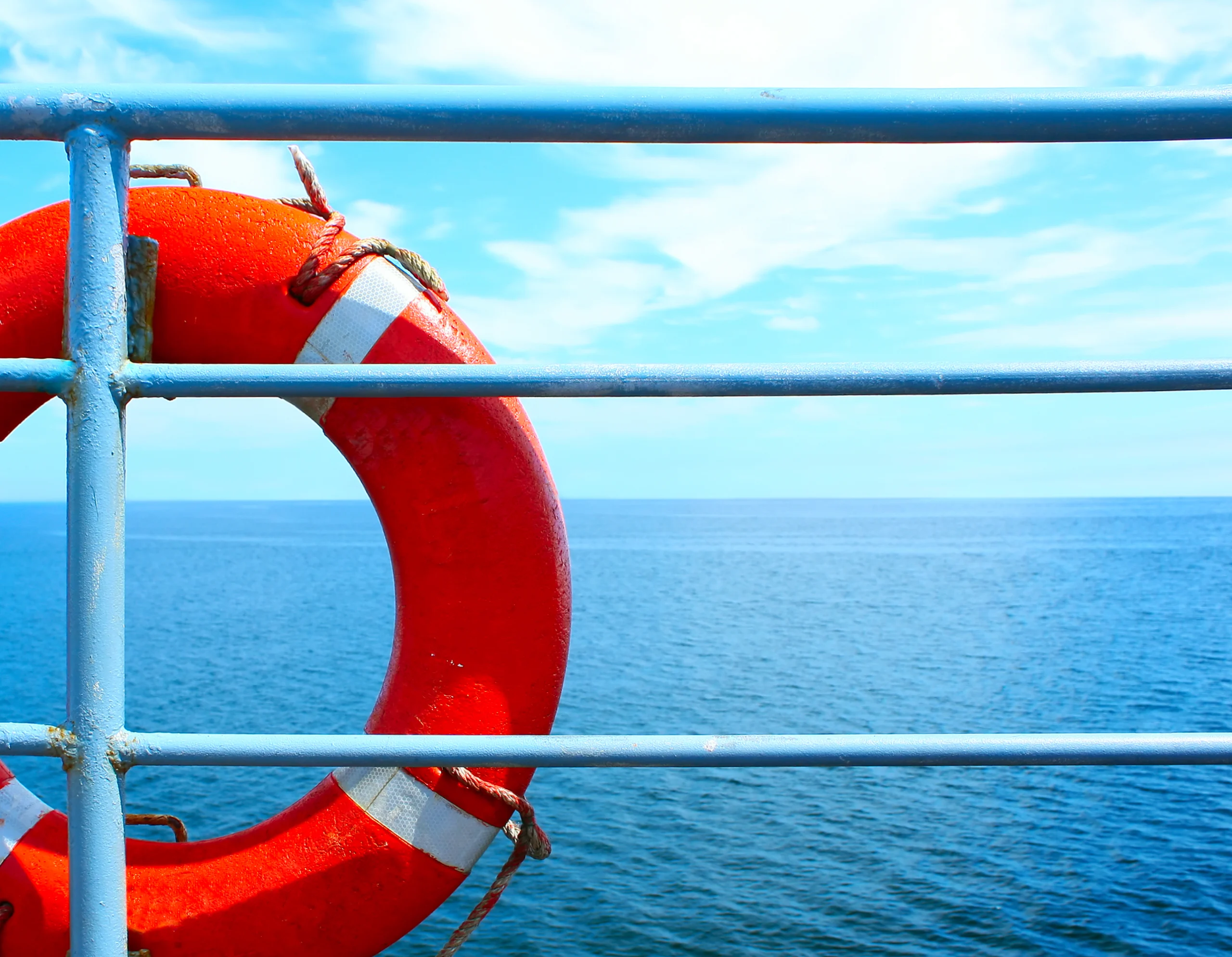 Red buoy on ship with blue sea and sky.