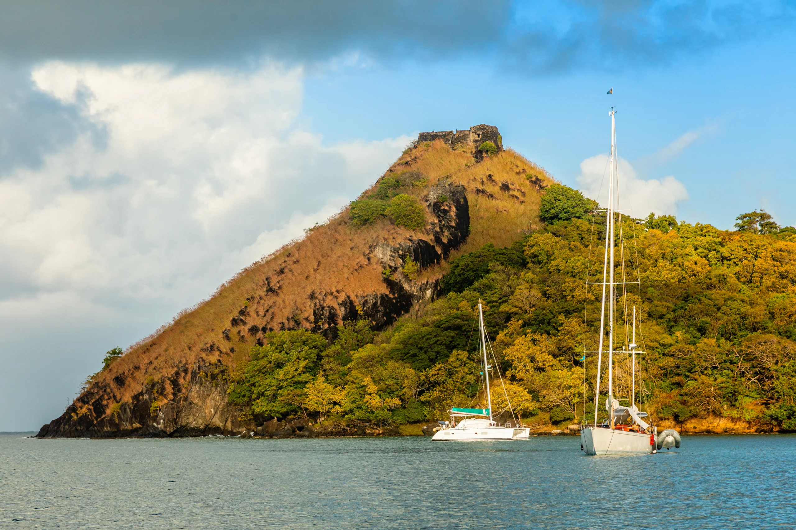 Yachts anchored at the Pigeon Island with fort ruin on the rock, Rodney bay, Saint Lucia, Caribbean sea.
