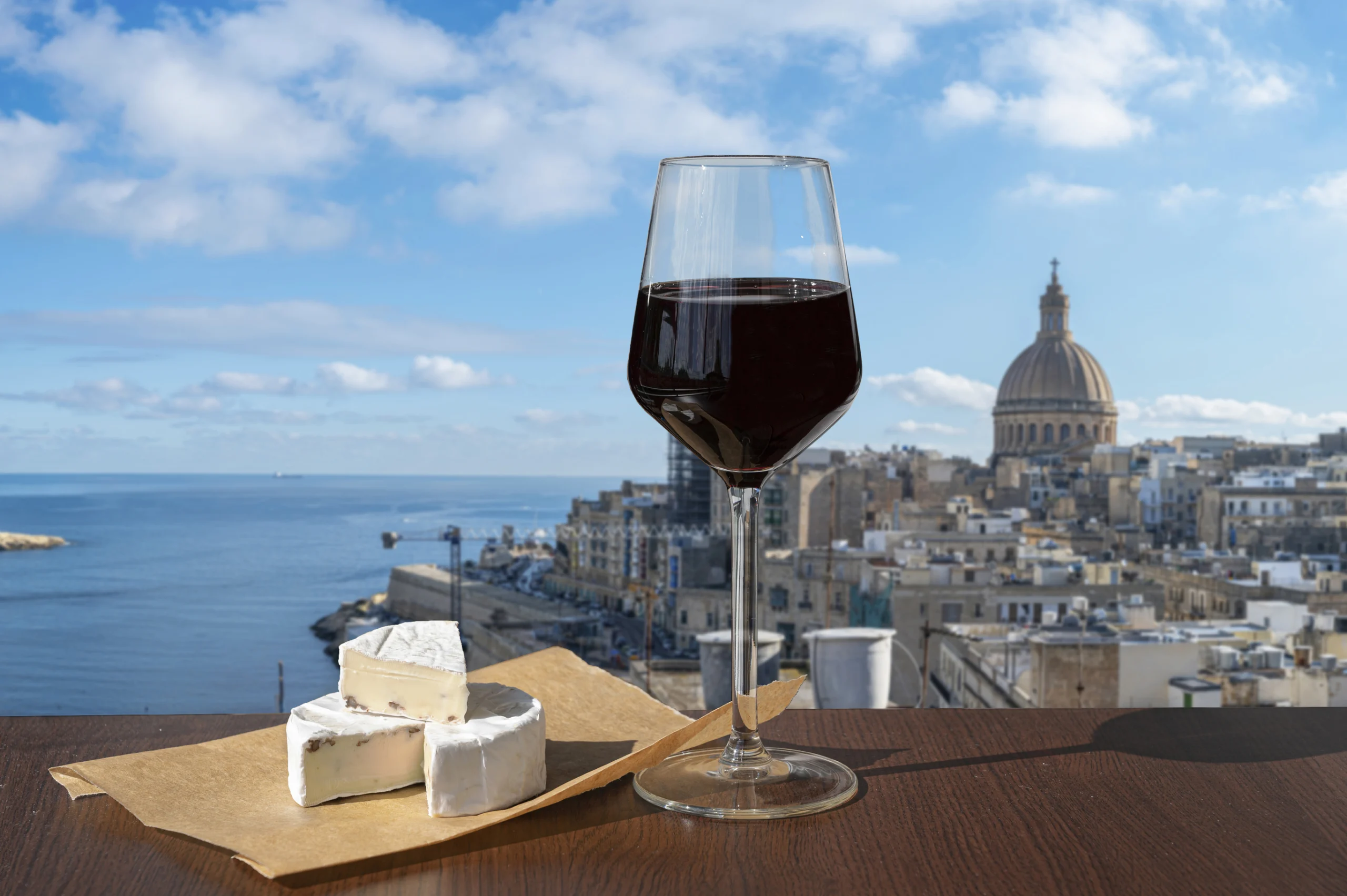 Glass of red wine with cheese with view of Valletta old town and harbor in Valletta, Malta