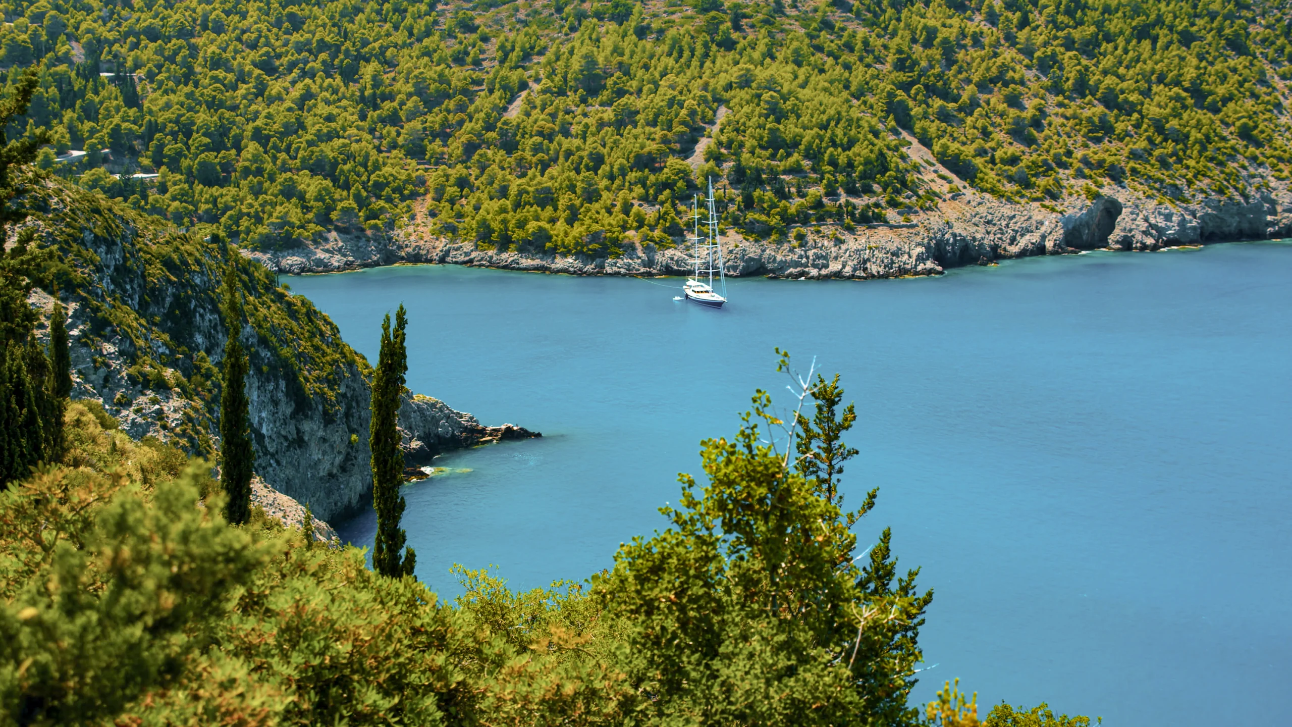 Aerial view of mountain forests and lagoons with a sailing yacht