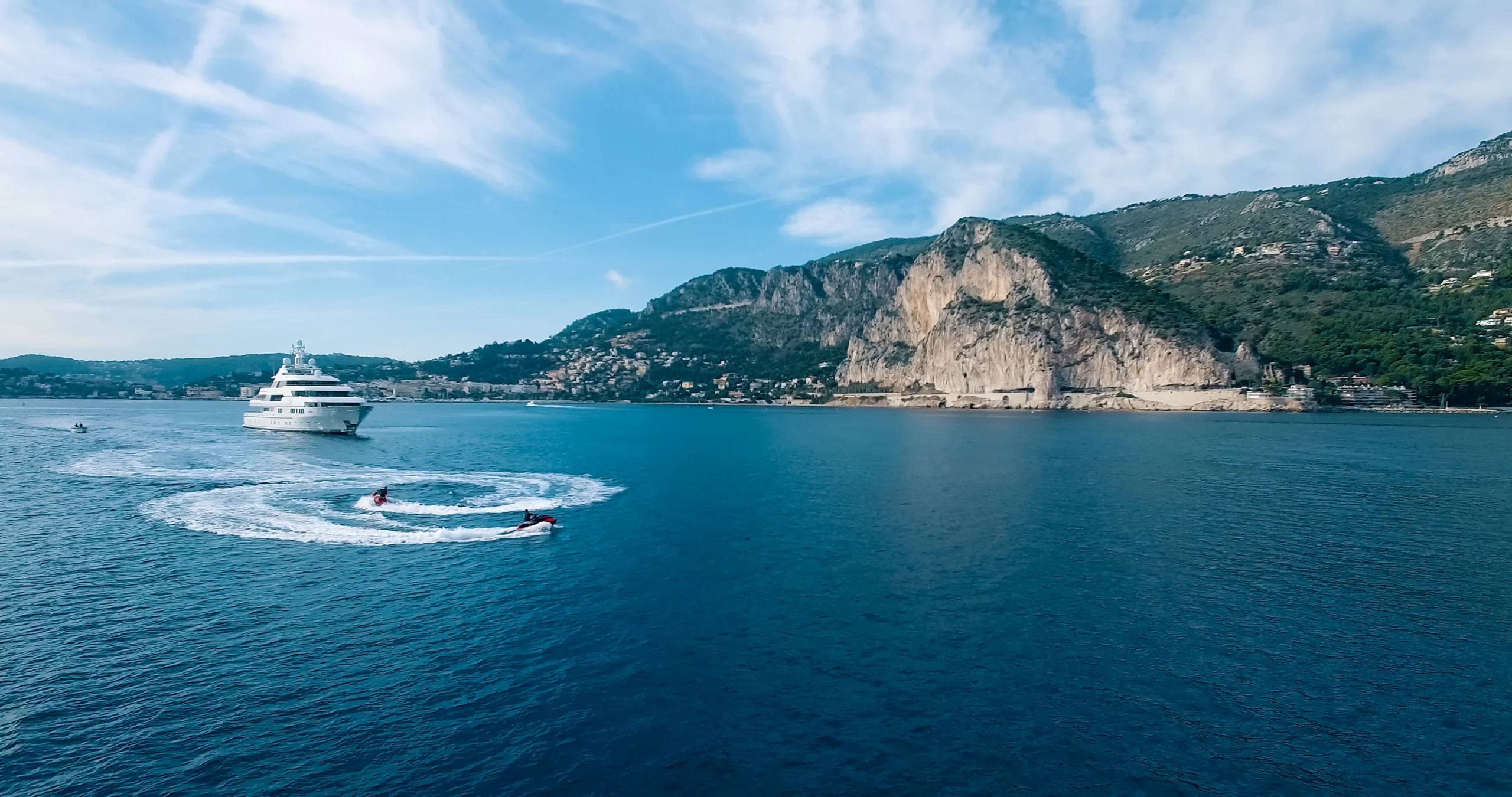 Aerial view of two jet-ski moving around large yacht