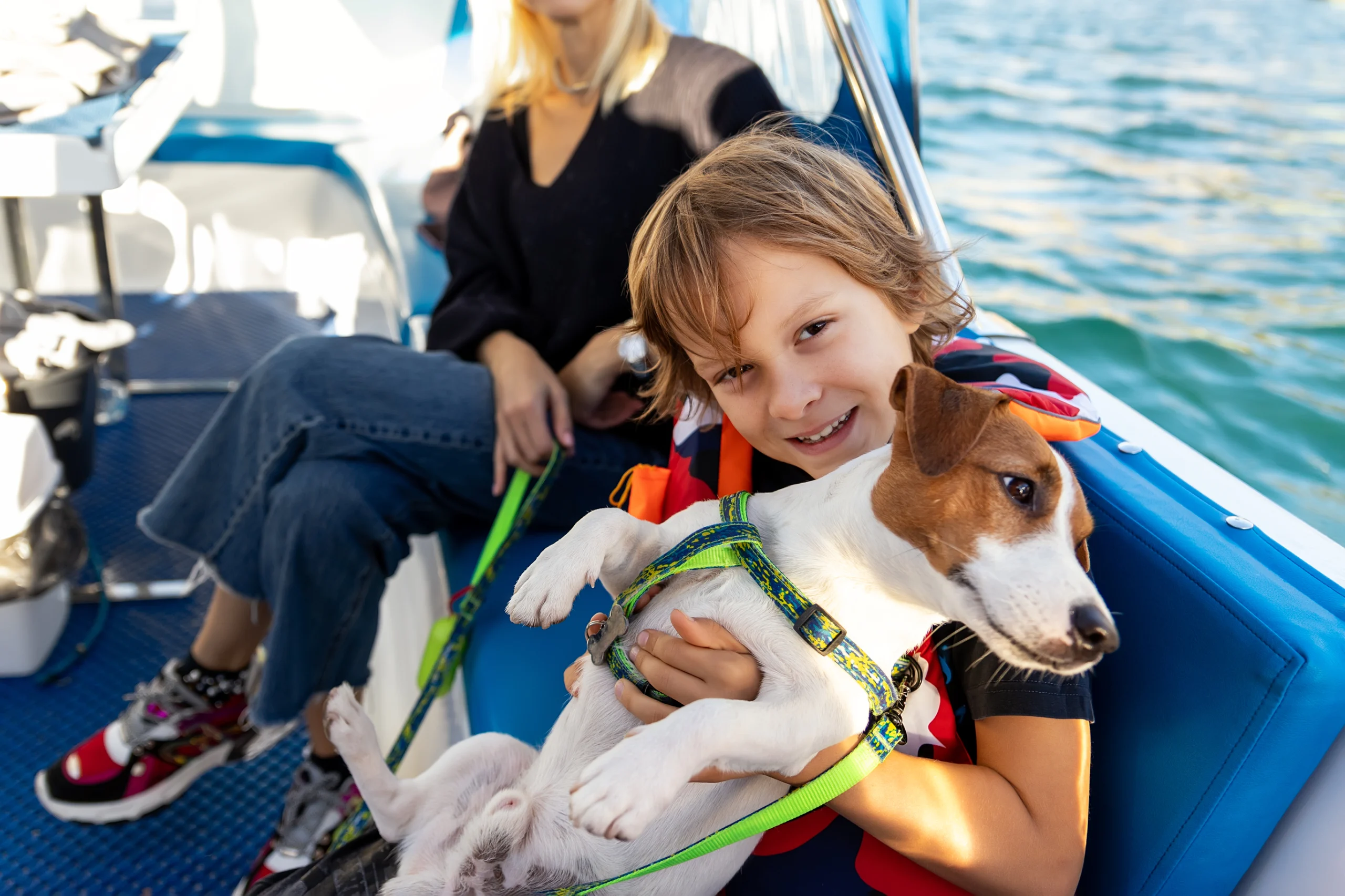 Portrait of cute little boy child enjoy petting cute adorable little jack Russel dog puppy sailing family luxury yacht boat