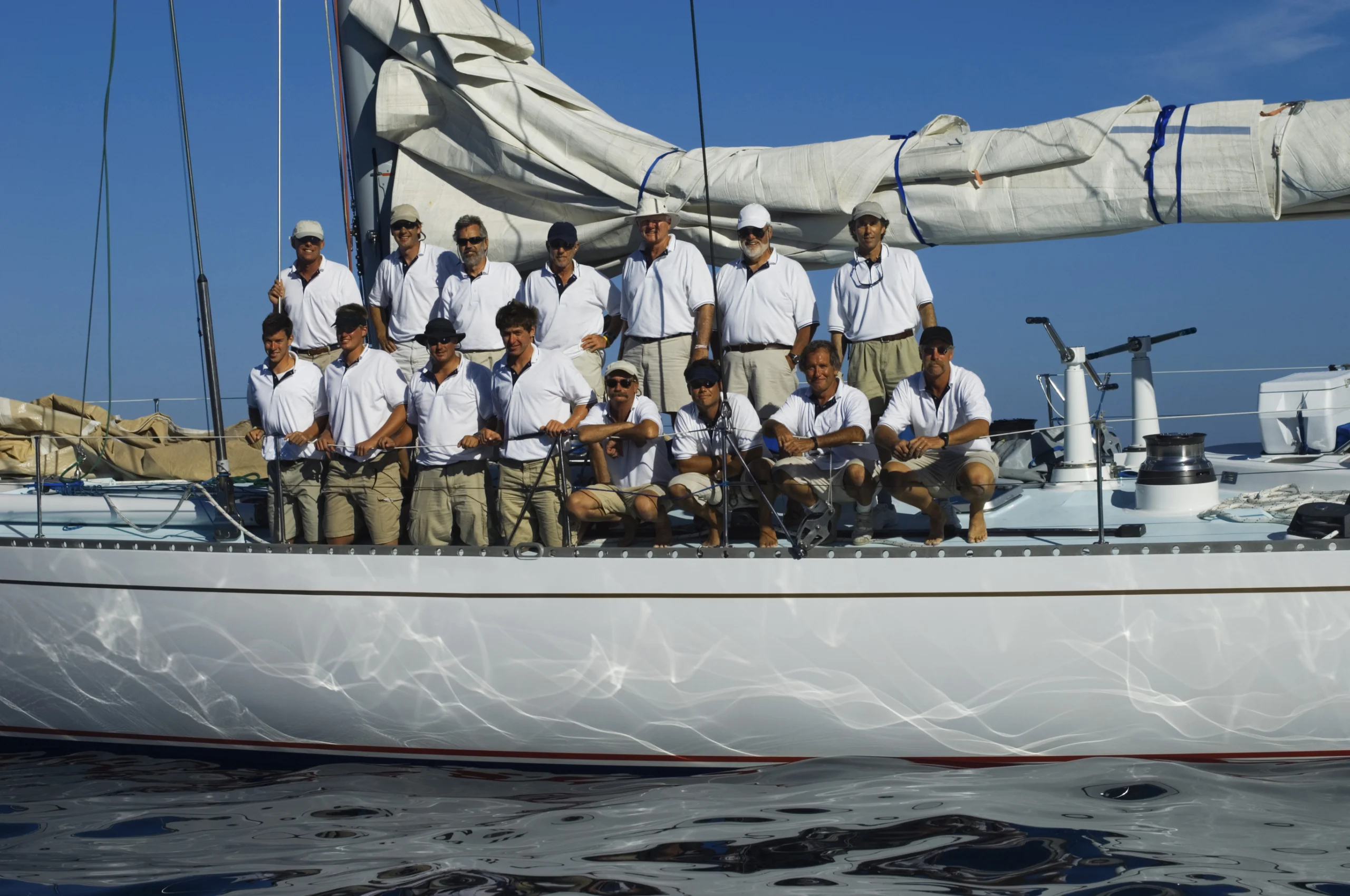 Group Portrait Of Sailing Crew On Board. Sailing crew posing for a group portrait on board against clear blue sky