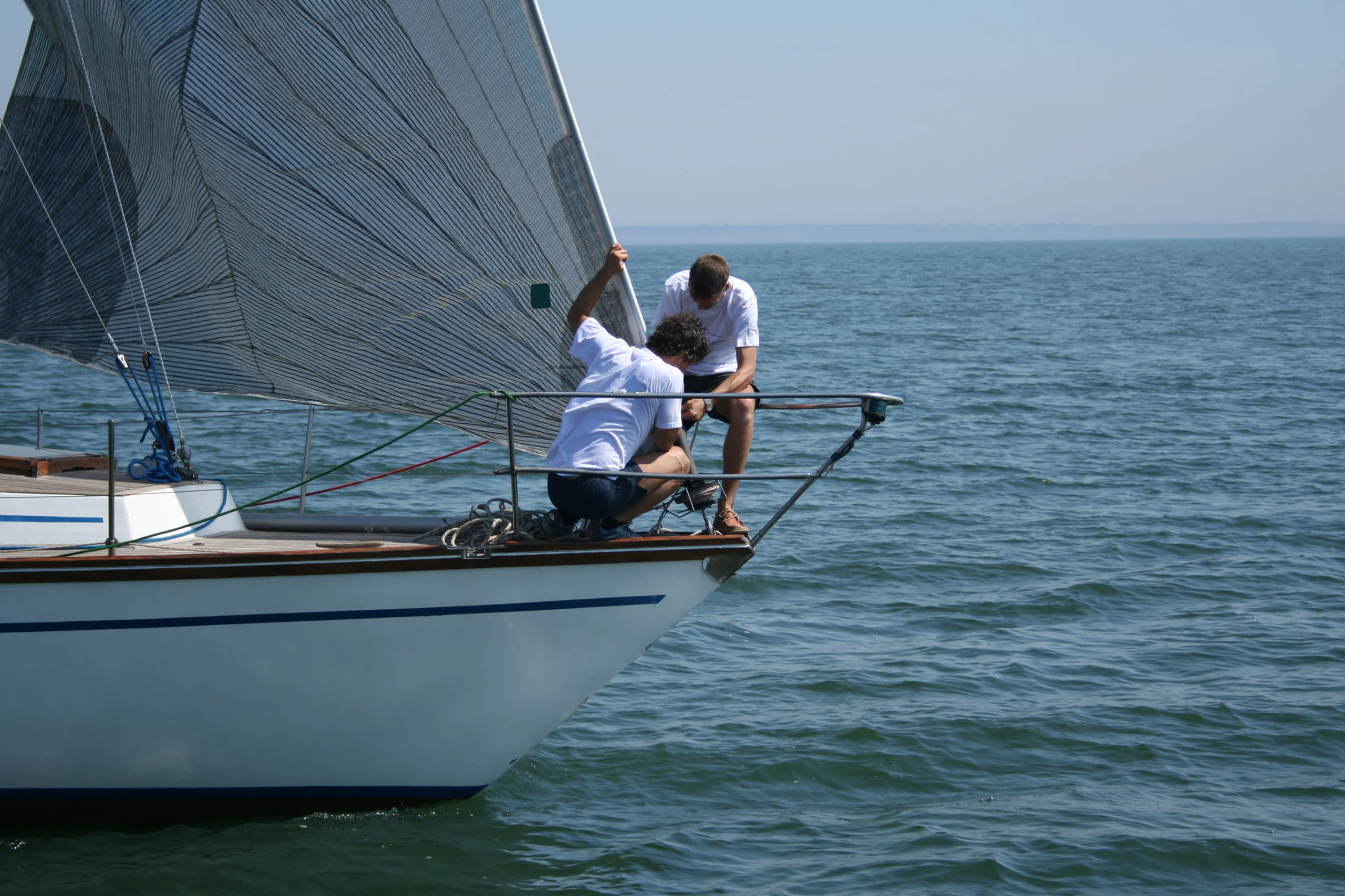 Two sportsmen work with sails. A regatta of yachts