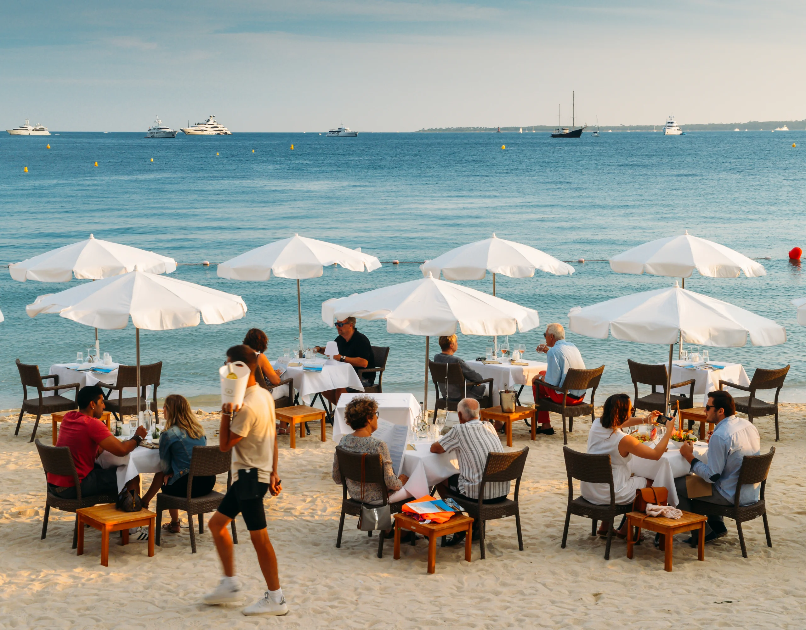 Couples have drinks and appetizers at a luxurious restaurant on the beach in the French Riviera resort town of Juan les Pins, Cote d`Azur, France