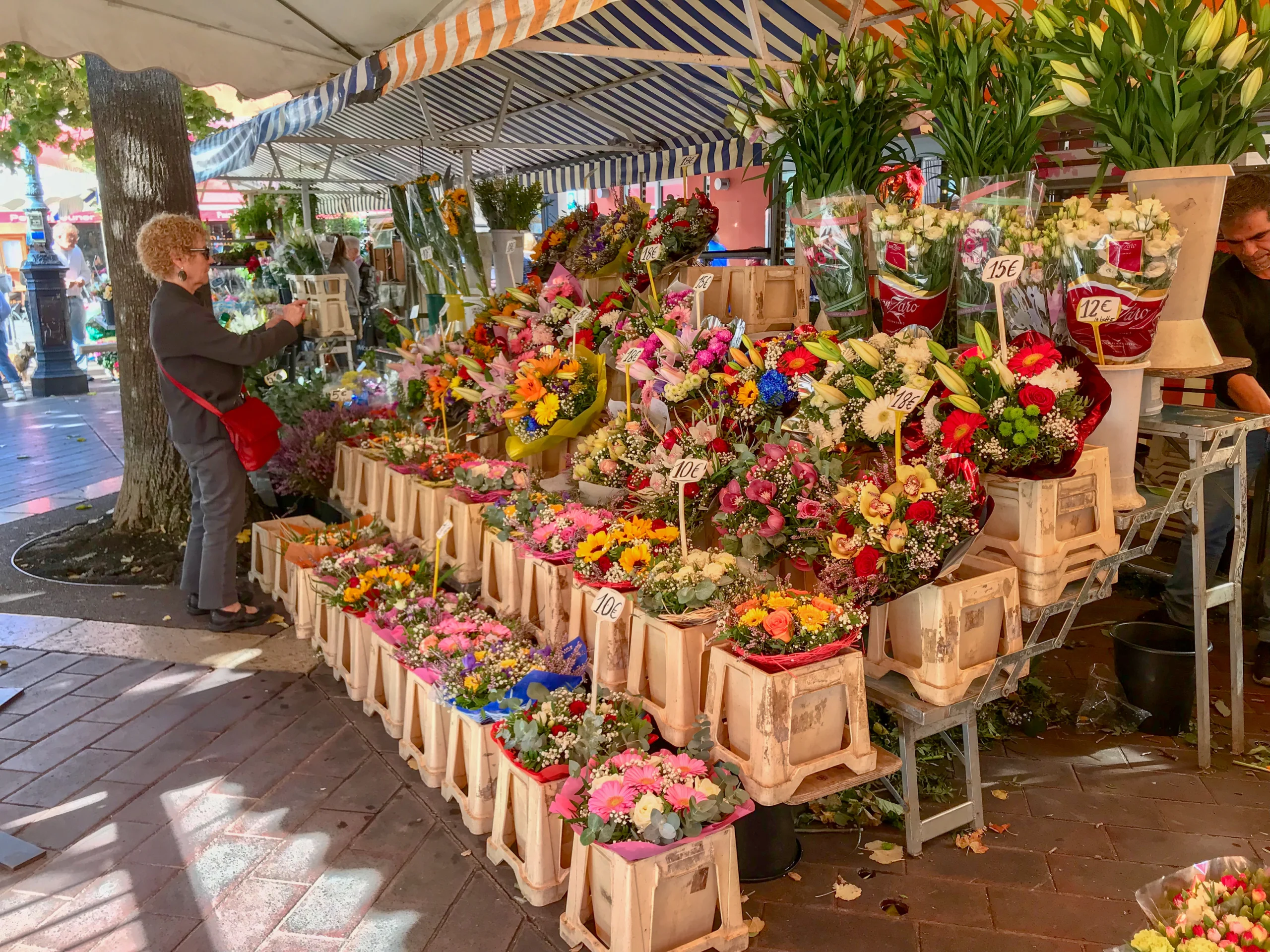 Oct 2017: Woman looks at blooms in an outdoor flower market in Nice, France