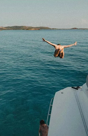 An image of a man diving to water from a yacht