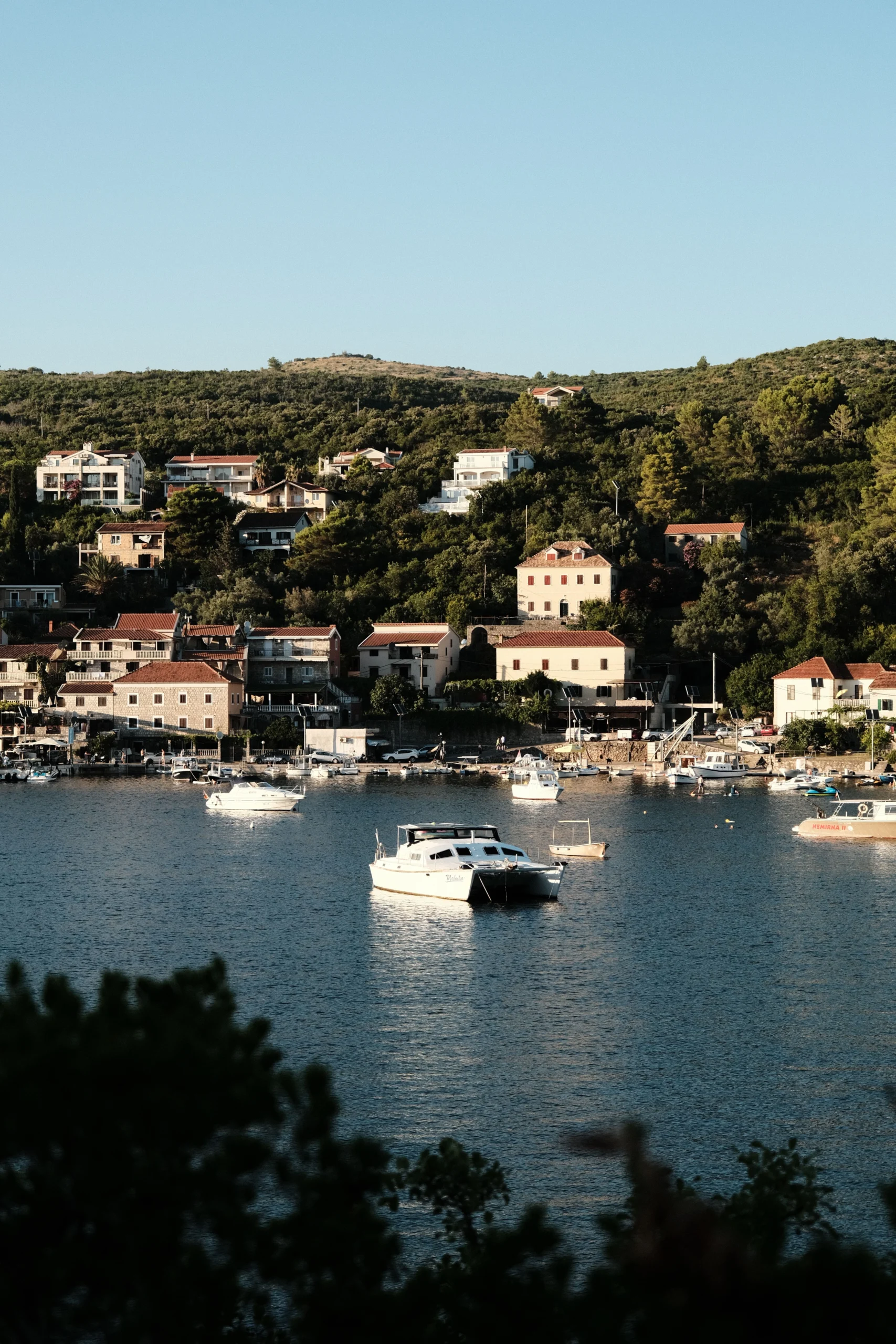 Charming view of Bigova's marina with boats and coastal houses in Montenegro.