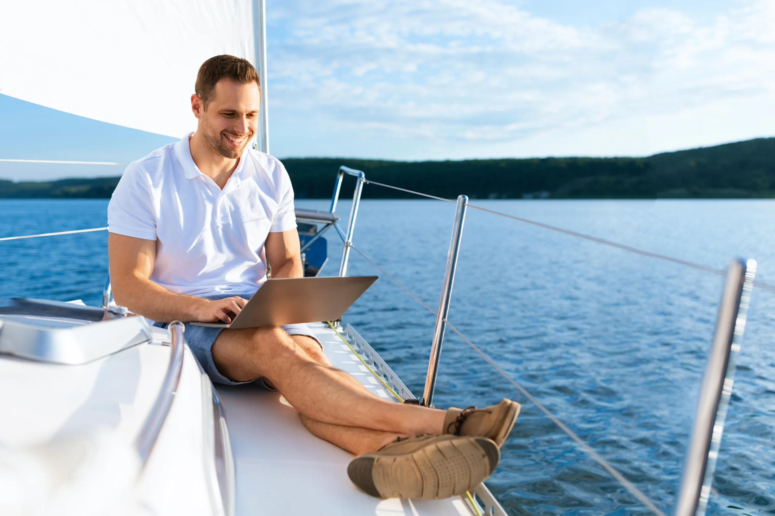 Happy Man On Yacht Sitting With Laptop Working On Sailboat. Happy Man On Yacht Sitting With Laptop Working Living On Sailboat During Summer. Liveaboard Tour. Empty Space For Text